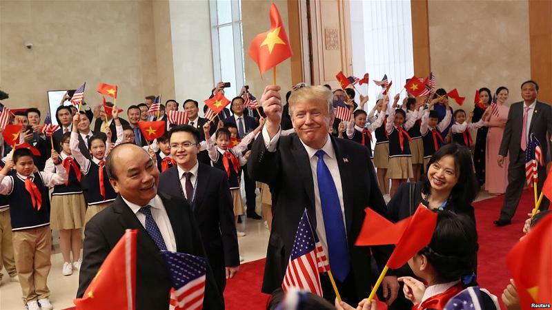 Tổng thống Donald Trump trao lá cờ Mỹ cho Thủ tướng Nguyễn Xuân Phúc và bản thân ông cầm lá cờ Việt Nam để vẫy chào đám 