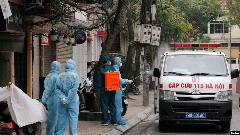 Tẩy rửa một xe cứu thương gần nhà một người nhiễm virus corona tại Hà Nội, 7 tháng Ba. (REUTERS)