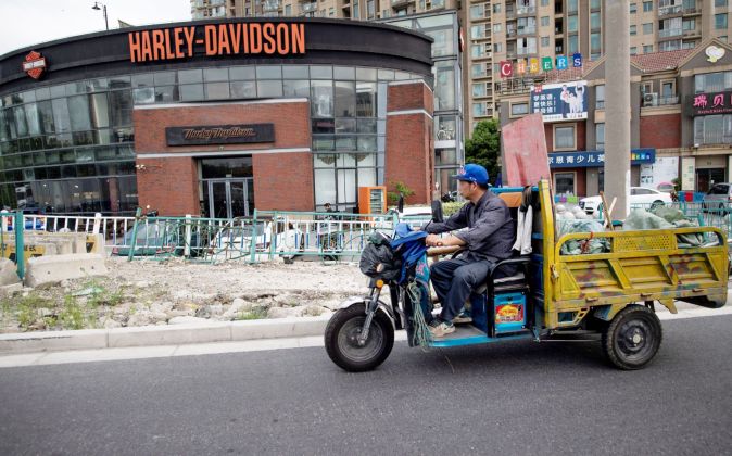 một người Trung Quốc chạy xe ngang cửa hàng của công ty sản xuất xe mô tô Harley-Davidson ở Thượng Hải.