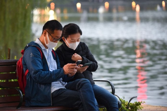 Hai du khách đeo khẩu trang khi đang ngồi nghỉ chân bên bờ hồ Hoàn Kiếm, Hà Nội, hôm 30 Tháng Giêng, 2020