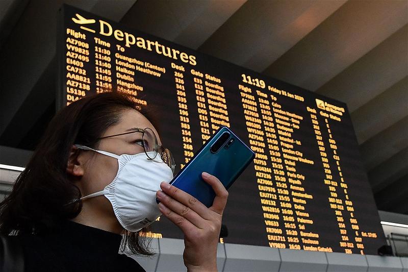 Một người phụ nữ Châu Á đeo khẩu trang tỏ ra lo lắng do bị hủy chuyến bay từ Italy về Trung Quốc đại lục vào ngày 30 Thá
